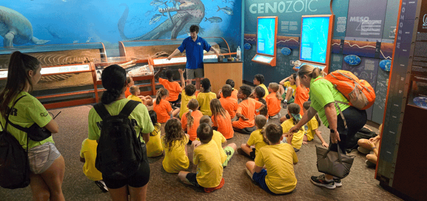 Image of an employee of The Bishop Museum of Nature and Science giving a talk to a school field trip group.